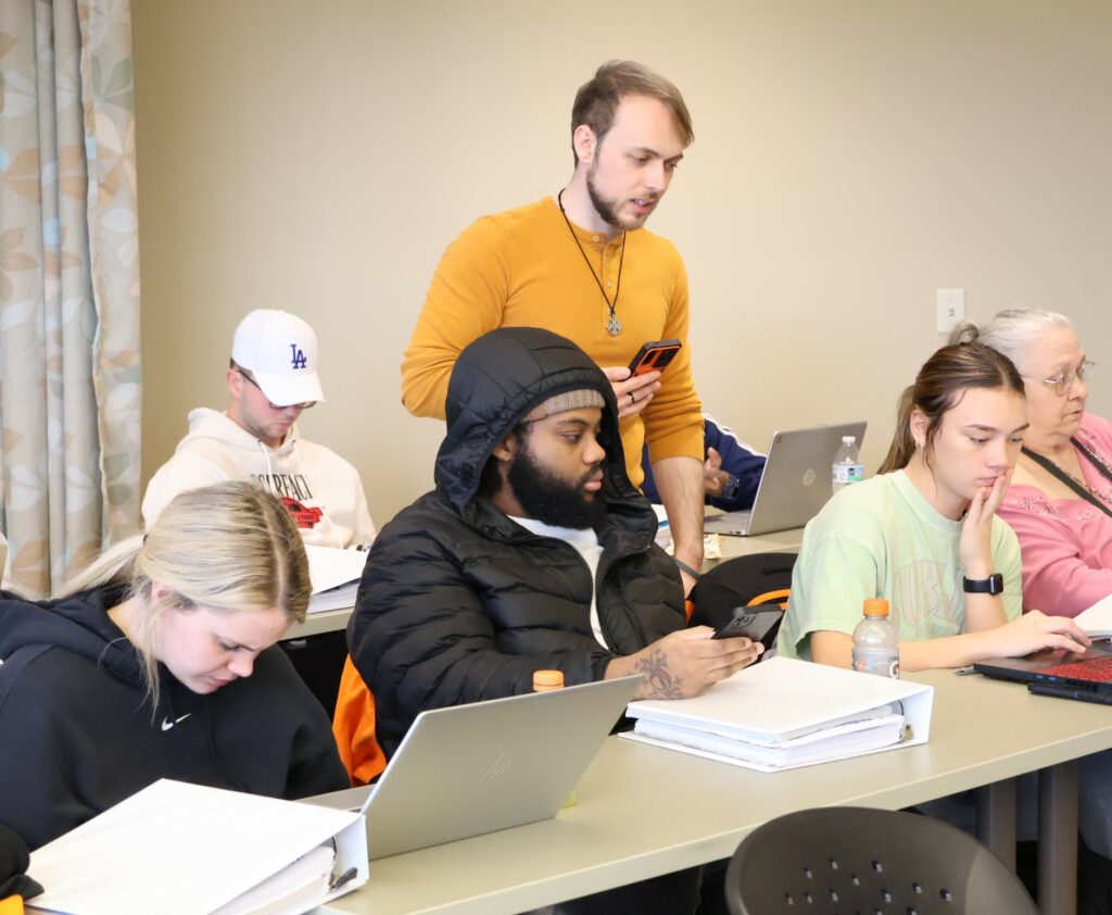 Tusculum staff member Justice Upp, standing, helps students and community volunteers in the VITA training class.