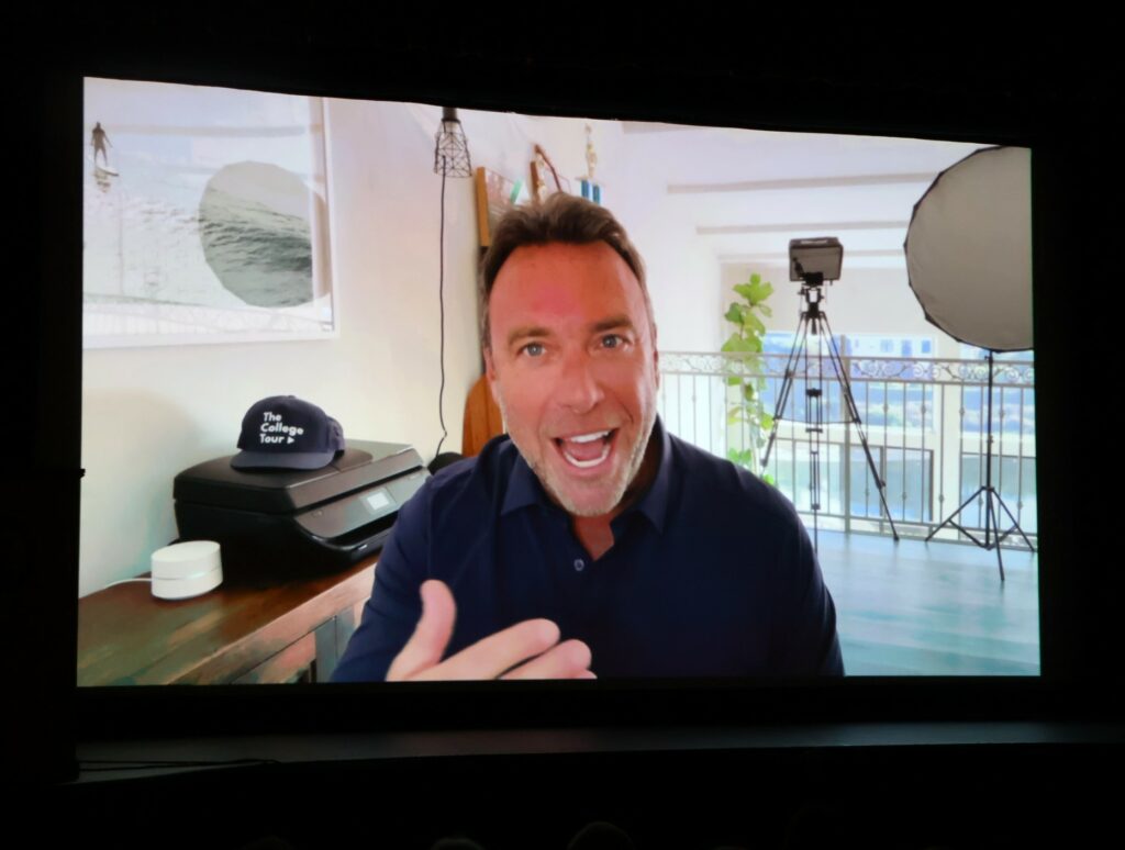 Alex Boylan, host of "The College Tour," greets the audience in a recorded message.