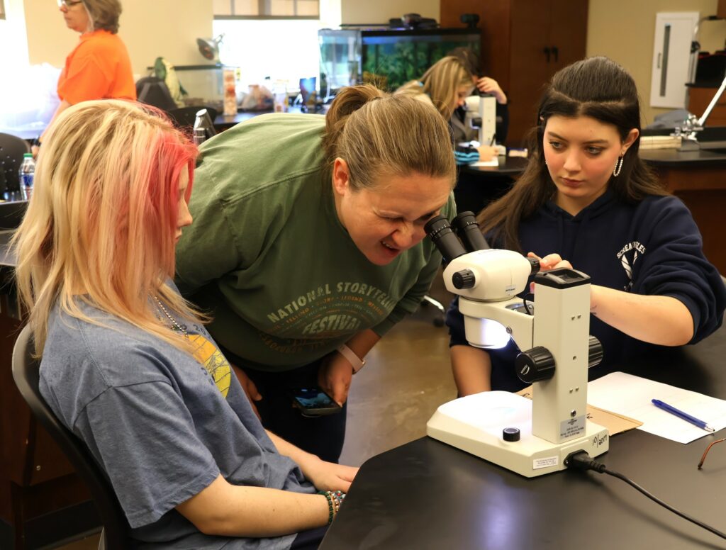 Lynnea Salinas, programs manager for Girl Scouts of the Southern Appalachians, looks at a water sample through a microscope.