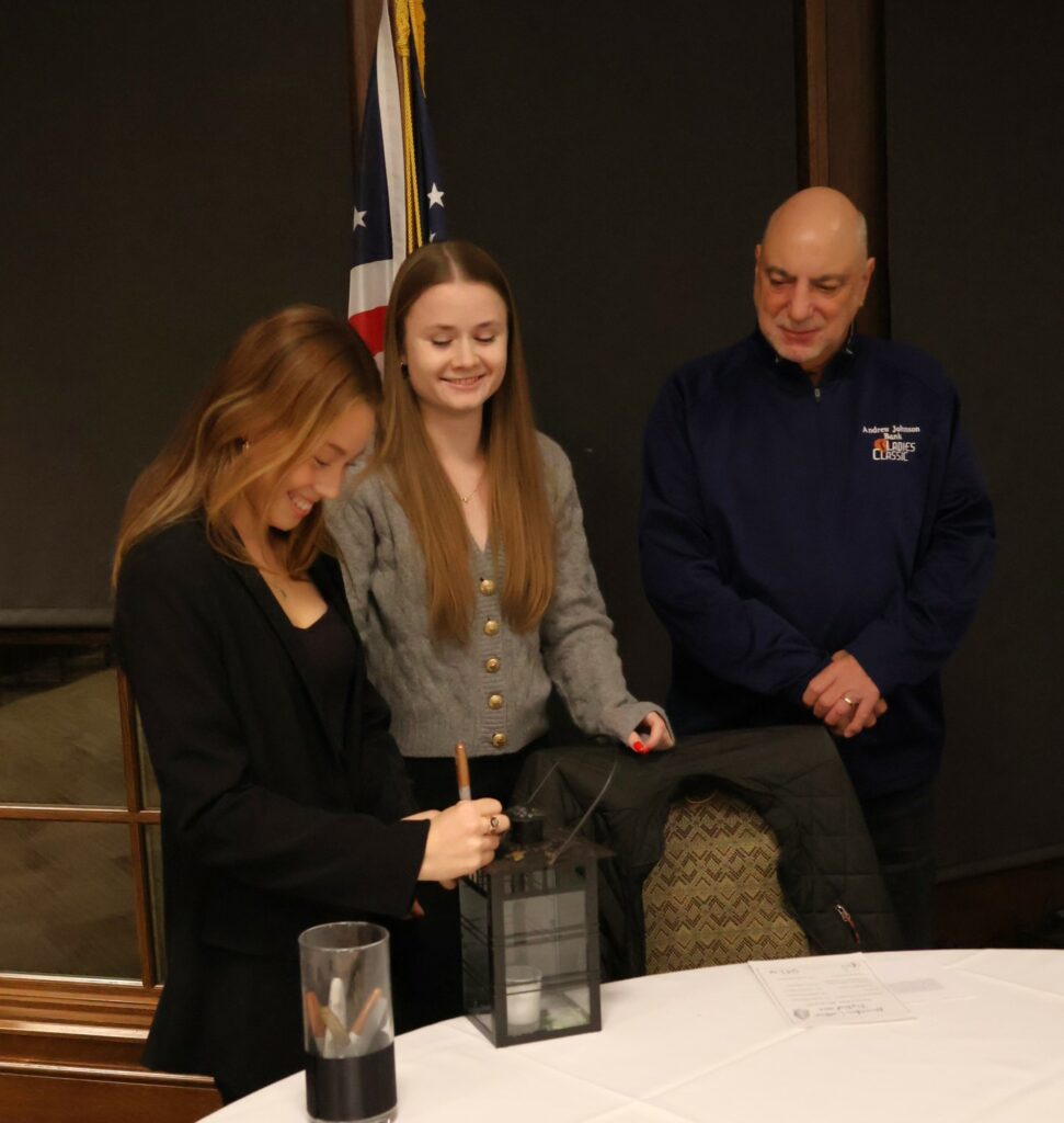Paulina Loretz signs the lantern, as Elodie Bachelor, middle, and Angelo Botta watch.