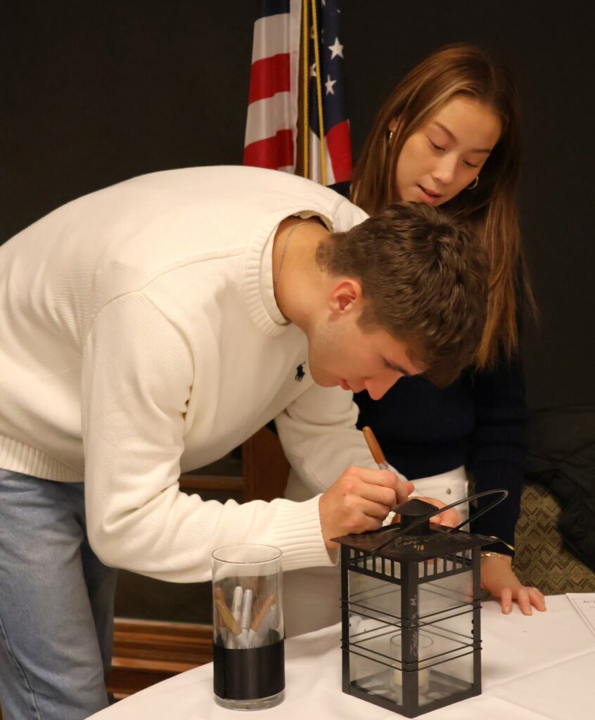 William Gee signs his lantern as Valentina Loretz watches.