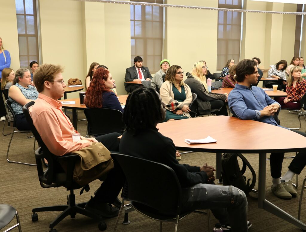Students, faculty members and family members listen.