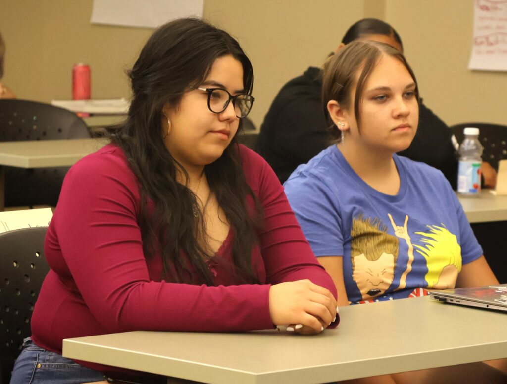 Two students listen as Jamey Anderson teaches the forensics class.