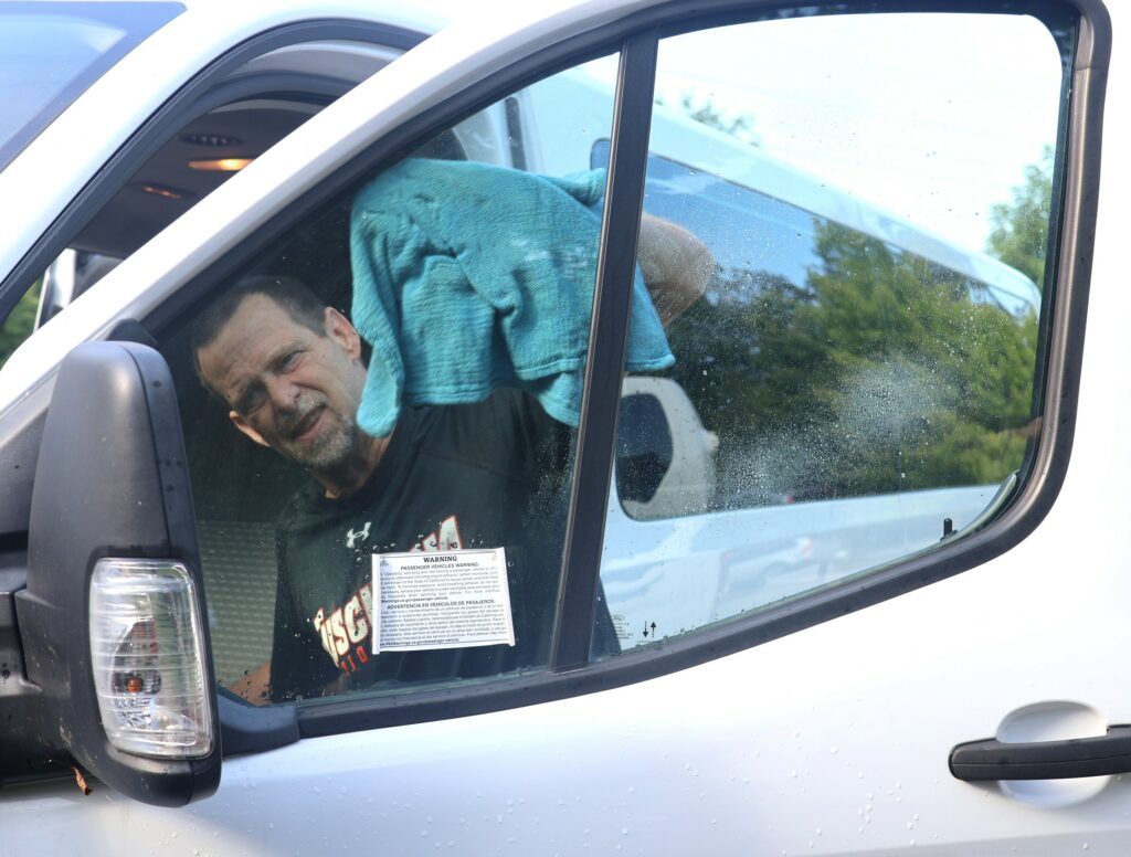 An employee wipes a vehicle window.