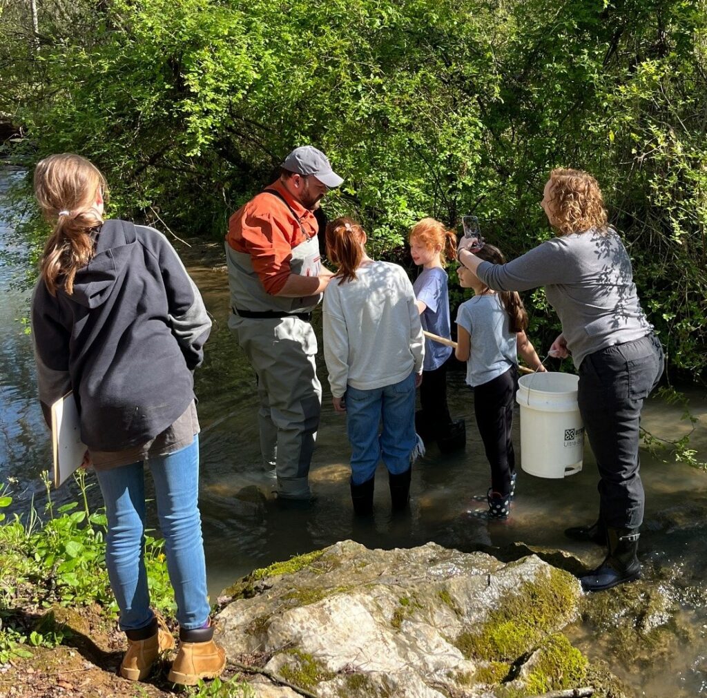 Girl Scouts collect water samples from College Creek. Assisting them are Jordan Baker, second from the left, and Dr. Kate Smith, right, both of whom are Tusculum professors.