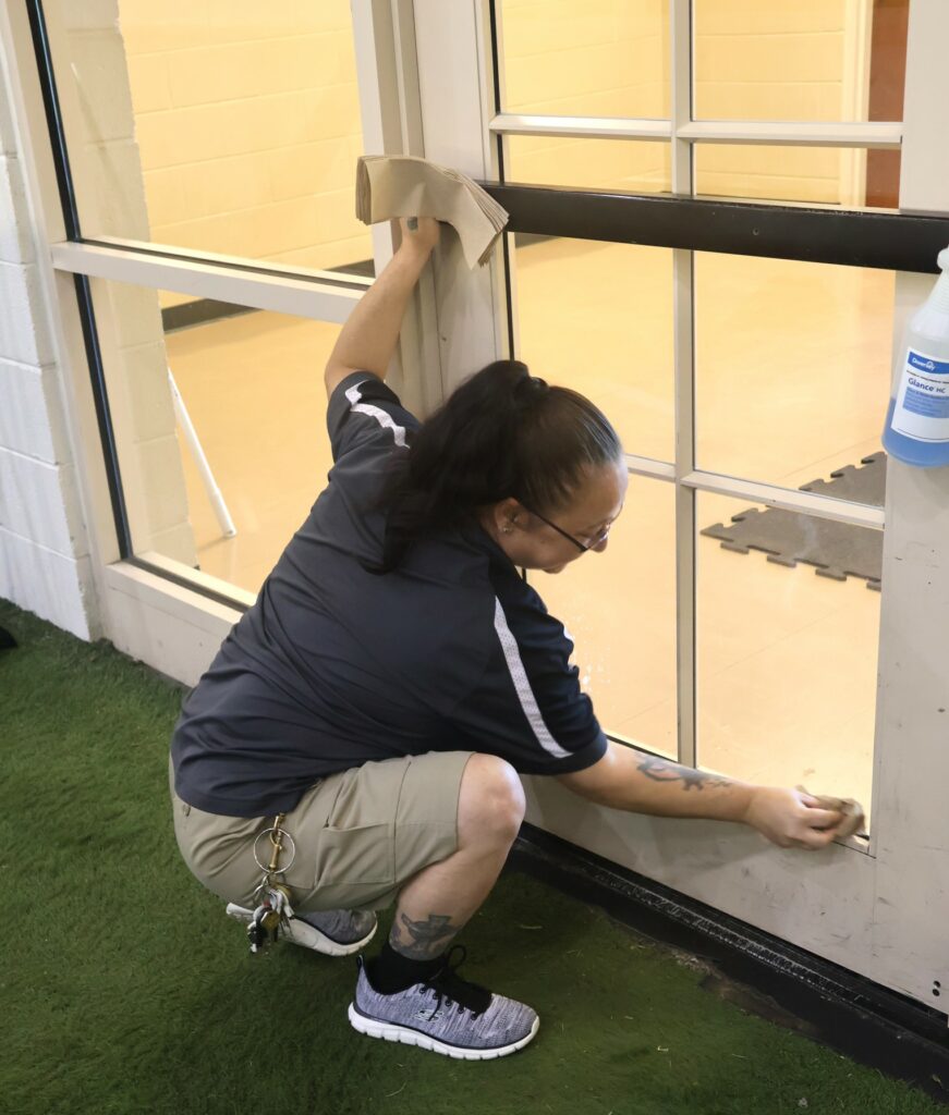 An employee wipes windows.