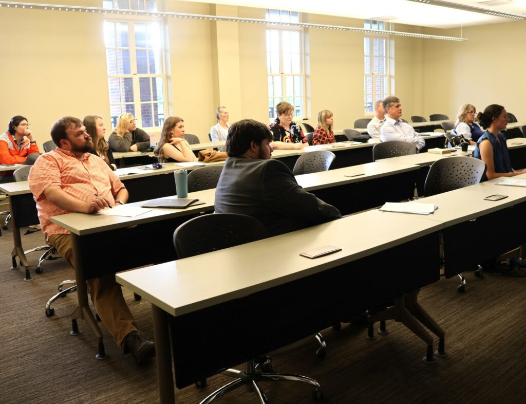 Students, faculty and staff listen to presentations.