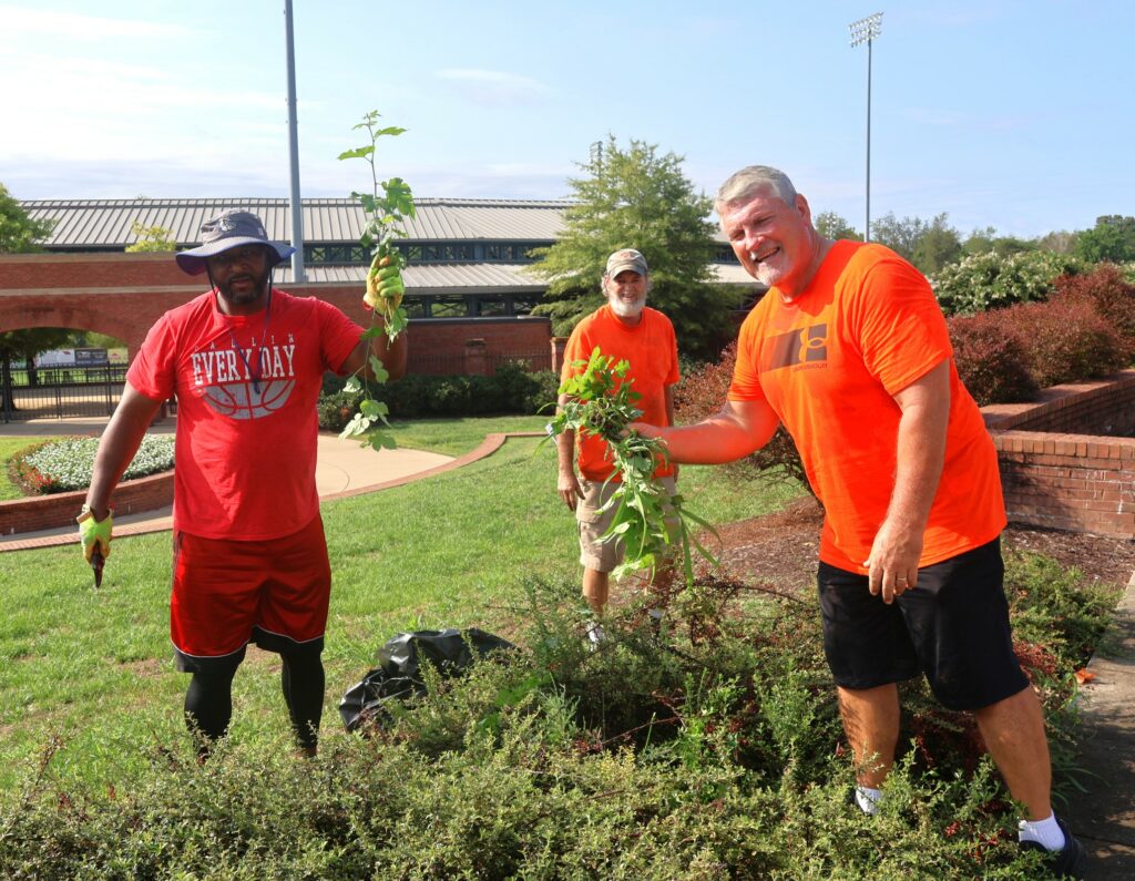 Steve Anderson, left, Tusculum’s multicultural retention coach; and Billy Taylor, right, the head football coach, show off some of their landscaping work as Todd Hertel from the Facilities Management Department stands in the background.