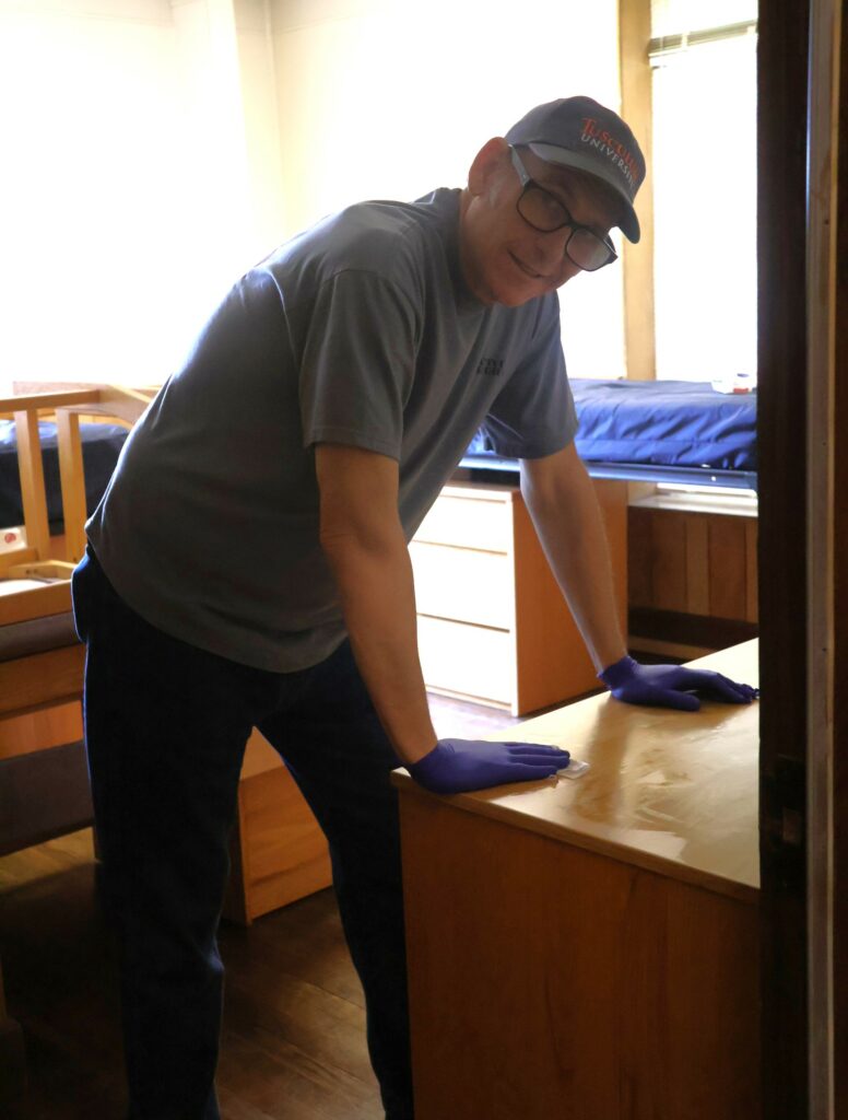 Ed Breese wipes a student desk.