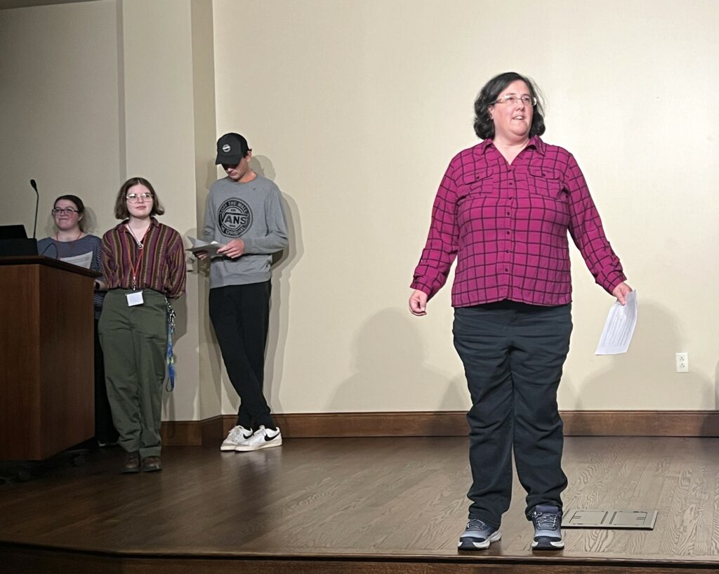 Dr. Anne Acker introduces the students participating in the reading of "Pygmalion."