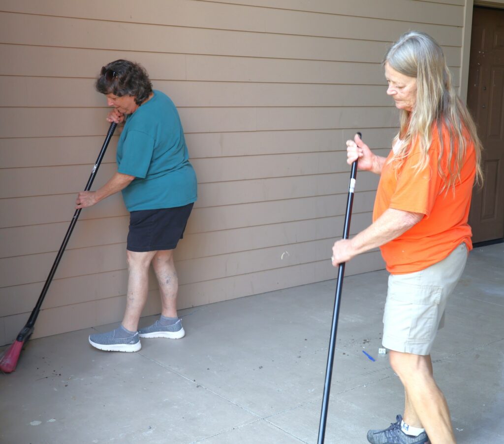 Rose Webb, left, and Linda Bible sweep a floor.