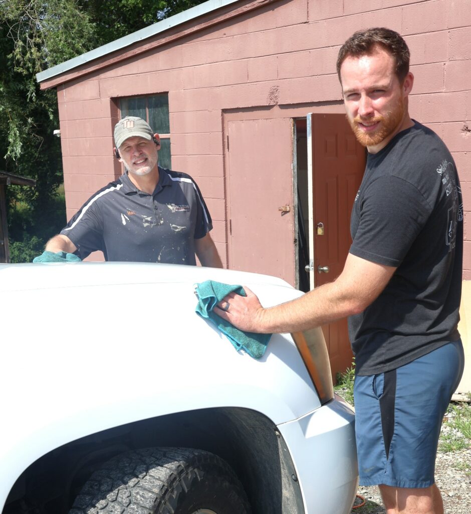 Two employees clean a Tusculum vehicle.