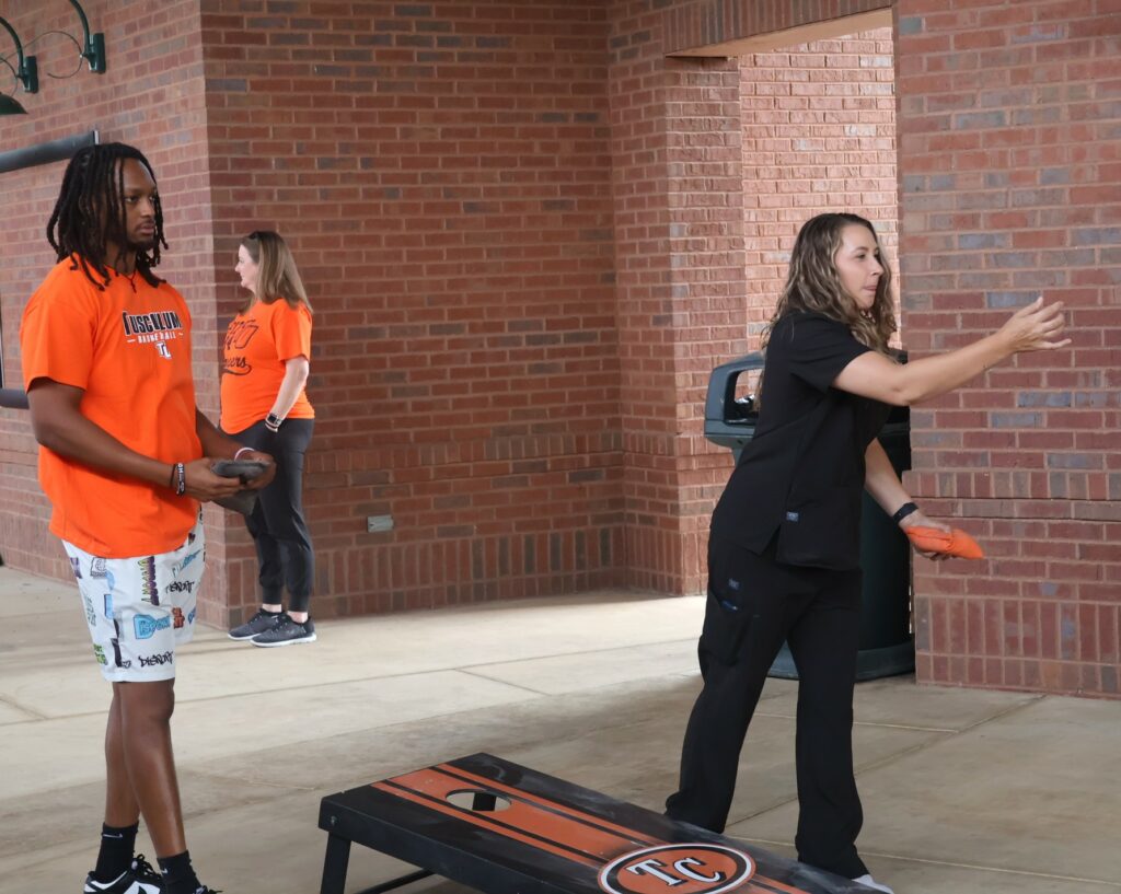 Trinity Velasco, right, tosses a cornhole bag.