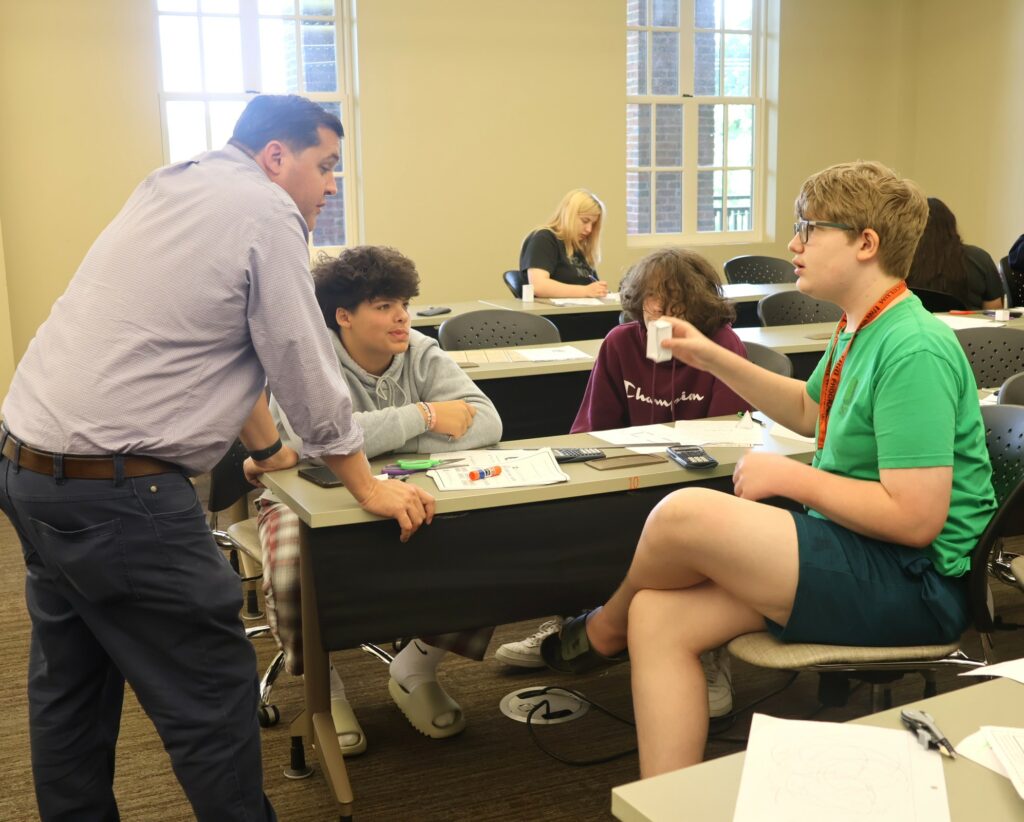 Lucas Stinson, left, speaks with students in his math class.