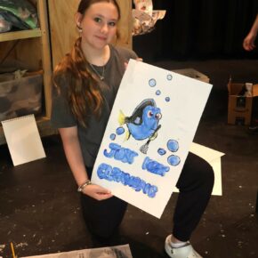 A girl shows the sign she made during Theatre Camp in 2024.