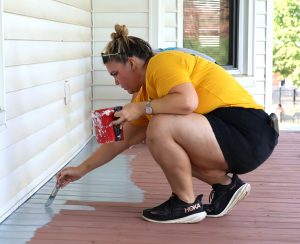 Erin Frizzell paints a porch outside a house that will be used for Tusculum’s new Discipleship Living-Learning Center.