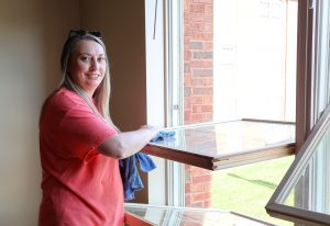 Dr. Melissa Bryant cleans a window in a university apartment.