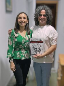 Rouja Green, left, and Doncho Donchev take time for a photo in Bulgaria in the fall during an exhibit of his work. He is holding the book “Persona Satyricona,” which he will discuss at Tusculum.