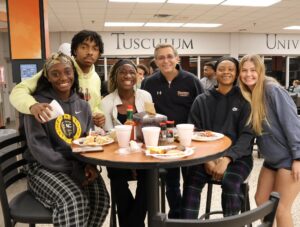 Dr. Scott Hummel, third from the right, visits with students during the Midnight Breakfast event held during finals week.