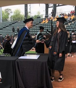 Dr. Hummel passing a diploma to a student