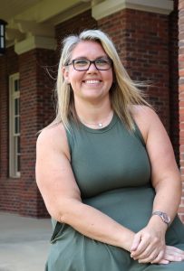 Erin Frizzell, sitting outside the Meen Center, has been promoted to dean of students.