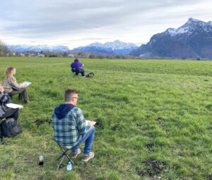 Trip participants draw en plein air with a view of the Alps in Austria.