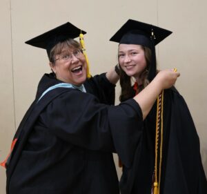Jill Oberfeitinger places graduation cords on Mary Anne Cooper.