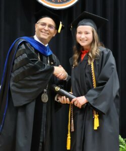 Mary Anne Cooper shakes hands with Dr. Scott Hummel, Tusculum’s president, during the university’s graduation ceremony.