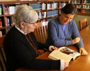 Kathy Hipps, director of the Thomas J. Garland Library, left, and Dr. Aja Matthews, assistant professor of sociology, look at the book “Diné: A History of the Navajos” by Peter Iverson.