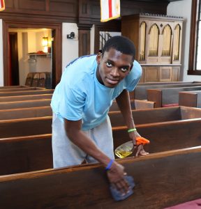 A student cleans a pew at St. James Episcopal Church.