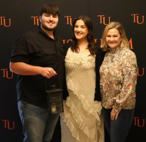 Jessica Silvers, center, presented a lantern to her brother, Tres, left, in April at Tusculum’s Lantern Festival. On the right is Trea King, cheer team head coach.