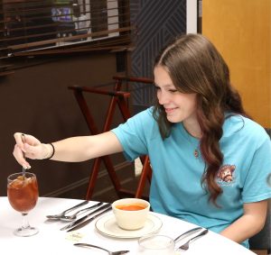 A student practices the best way to stir tea to which sugar has been added.