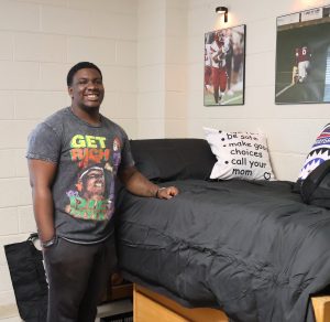 Malachi Monroe, a new student, stands in his residence hall room after moving in his belongings.