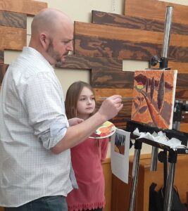 Two participants work on their painting during the 2024 event.