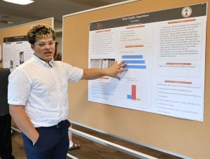 A student discusses a poster during the 2025 Summer Academy.