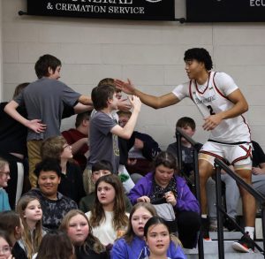 Tusculum University basketball player Bryce Jackson greets students in the stands after the game.