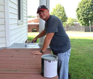 The Rev. E.J. Swatsell paints the porch of the male house of the Discipleship Living-Learning Center.