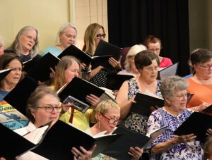 Female chorus members sing during rehearsal.