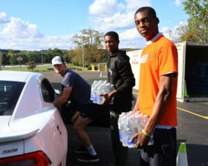 Left to right, Tusculum students Rasmus Nylander, Paul Nwigwe and Peter Nwigwe load water in a car at Chuckey-Doak Middle School.
