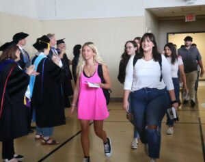 Students walk through Old Gym on their way to Pioneer Arena as faculty members clap.