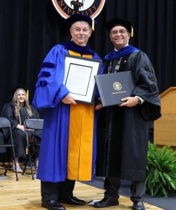 Dr. Greg Nelson, left, holds the board resolution awarding him the honorary doctorate, and Dr. Scott Hummel holds the diploma.