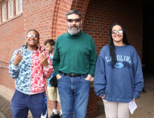 Left to right, student Sariah Johnson, Dr. Chuck Pearson and student Skylar Georges test out their glasses at the partial solar eclipse party.