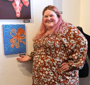 Student Mirissa Walters shows her dot painting in the exhibit.