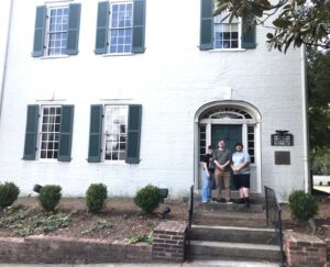 Left to right, Sydney May, Chris Colmer and Hughston Burnheimer stand in front of the main house at the President James K. Polk Home and Museum.