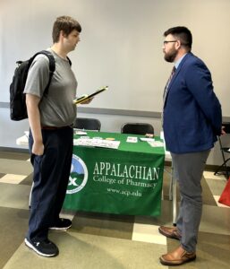 Tusculum student Aaron Smith, left, visits with a representative of the Appalachian College of Pharmacy. Photo by Tusculum student Landry Tea