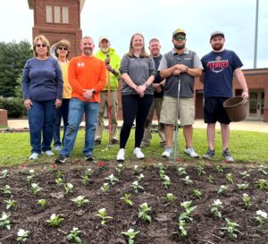 Representatives of Tusculum University, the Greeneville Lions Club and the Greeneville Flyboys planted the flowers outside Pioneer Park. Left to right are Susan Price, Nancy Southerland, Garrett Hensley, Todd Hertel, Carrie Maggert, Chad Grindstaff, Matt Bible and Brandon Bouschart.