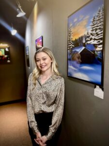 Mattie Vincent is one of the students working on the gala. Here, she is shown by some of her artwork during her senior capstone presentation this month.