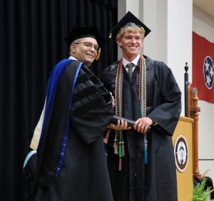 Jerry Ricker, right, the undergraduate student speaker, receives his congratulations from Dr. Scott Hummel after walking the stage.