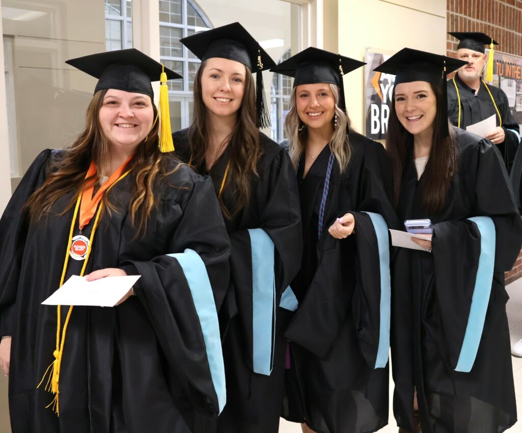 Four graduates are ready for the ceremony to start.