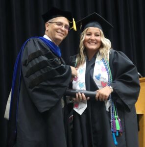 Shay Hess, right, receives congratulations from Dr. Hummel in honor of her bachelor’s degree.